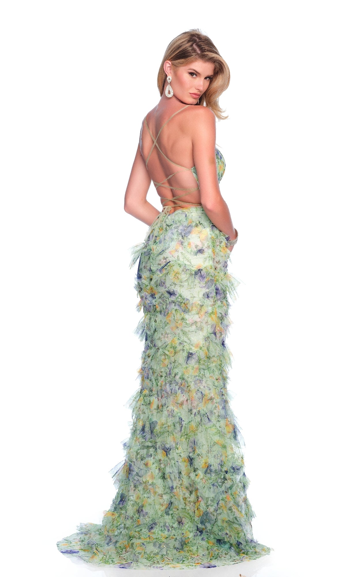 A woman models the Dave & Johnny 12092 Green Floral Prom Dress, featuring a backless crisscross-strap design and ruched bodice, against a plain white background.